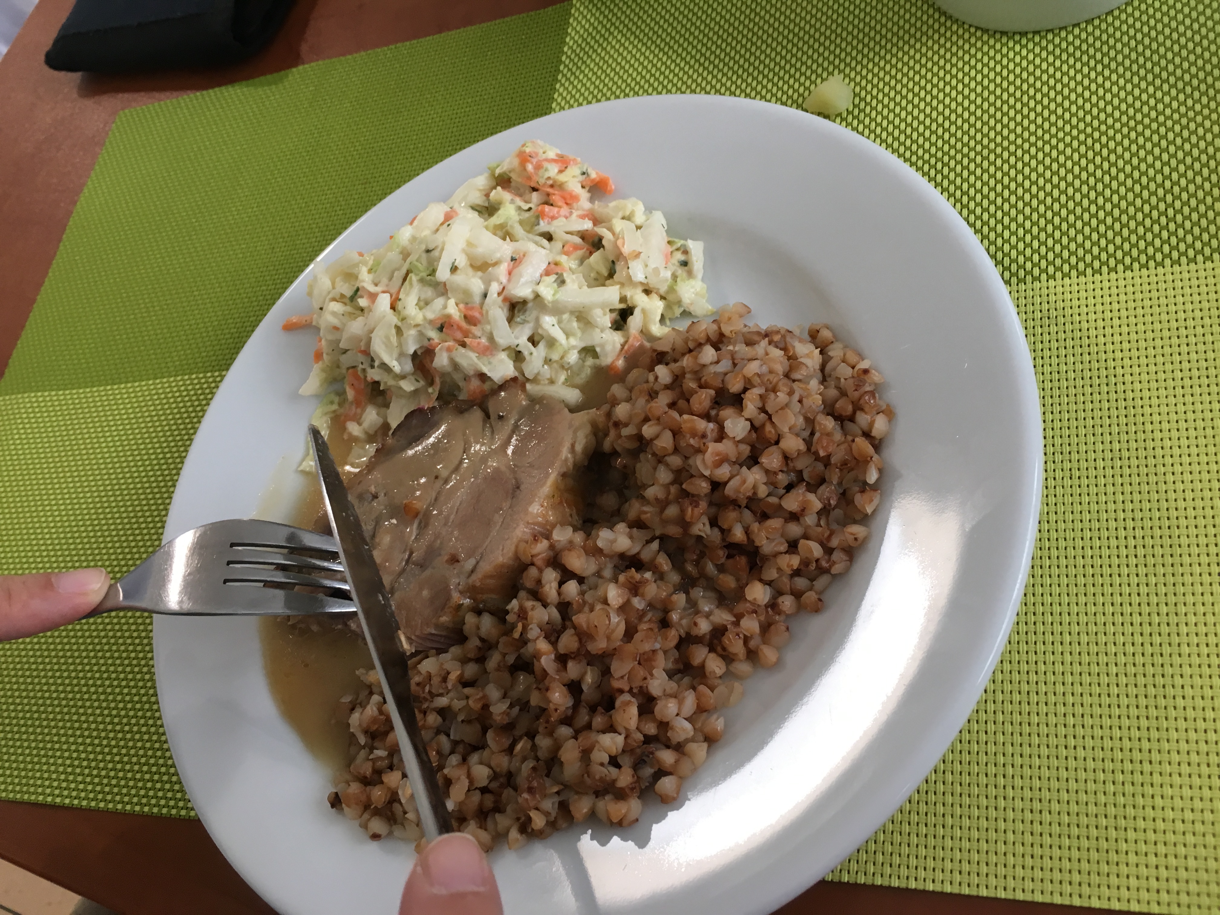 Smacznie i zdrowo – zdjęcie przedstawia biały talerz stojący na zielonej podstawce, a na nim kasza, porcja mięsa i surówki.